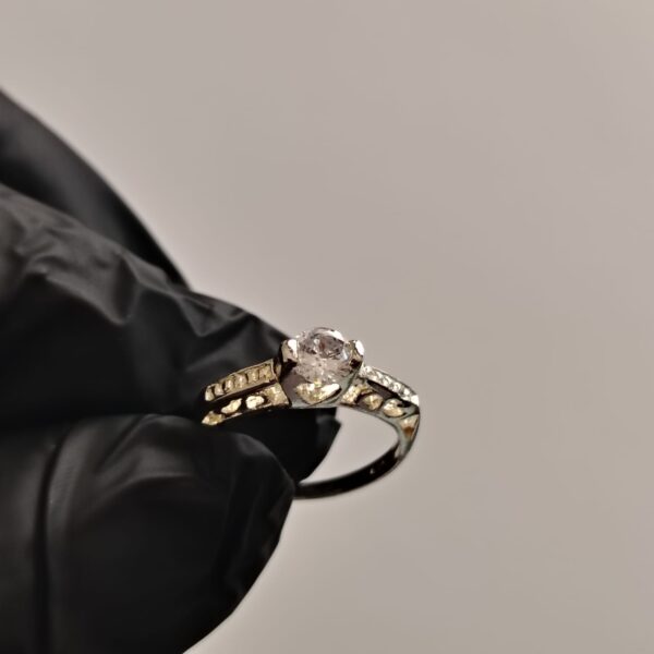 Anillo de plata con piedra preciosa grande y piedras pequeñas incrustadas con detalle de corazones